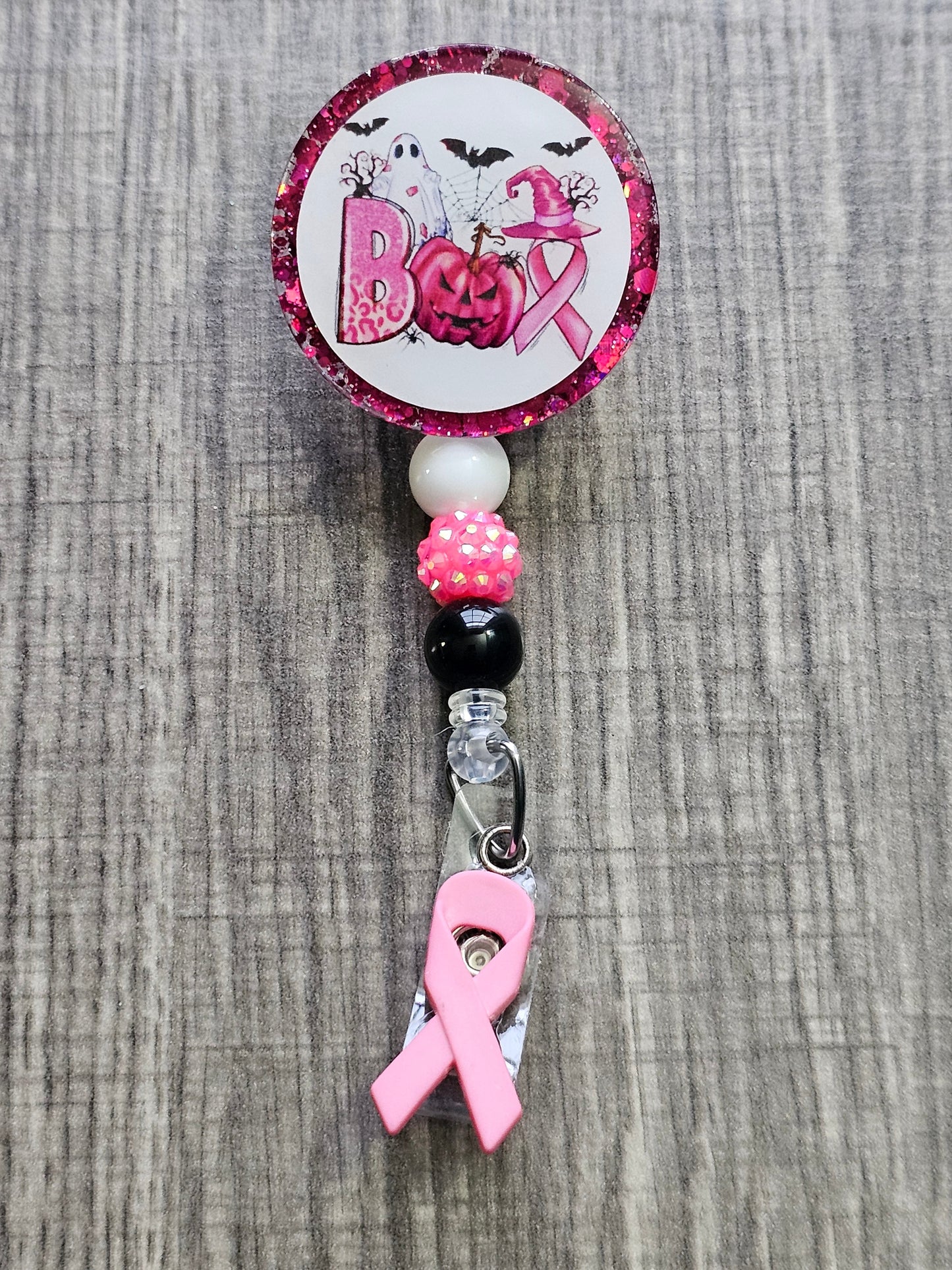 A Halloween themed Badge Reel with the word BOO decorated in a Halloween theme and Breast Cancer awareness theme