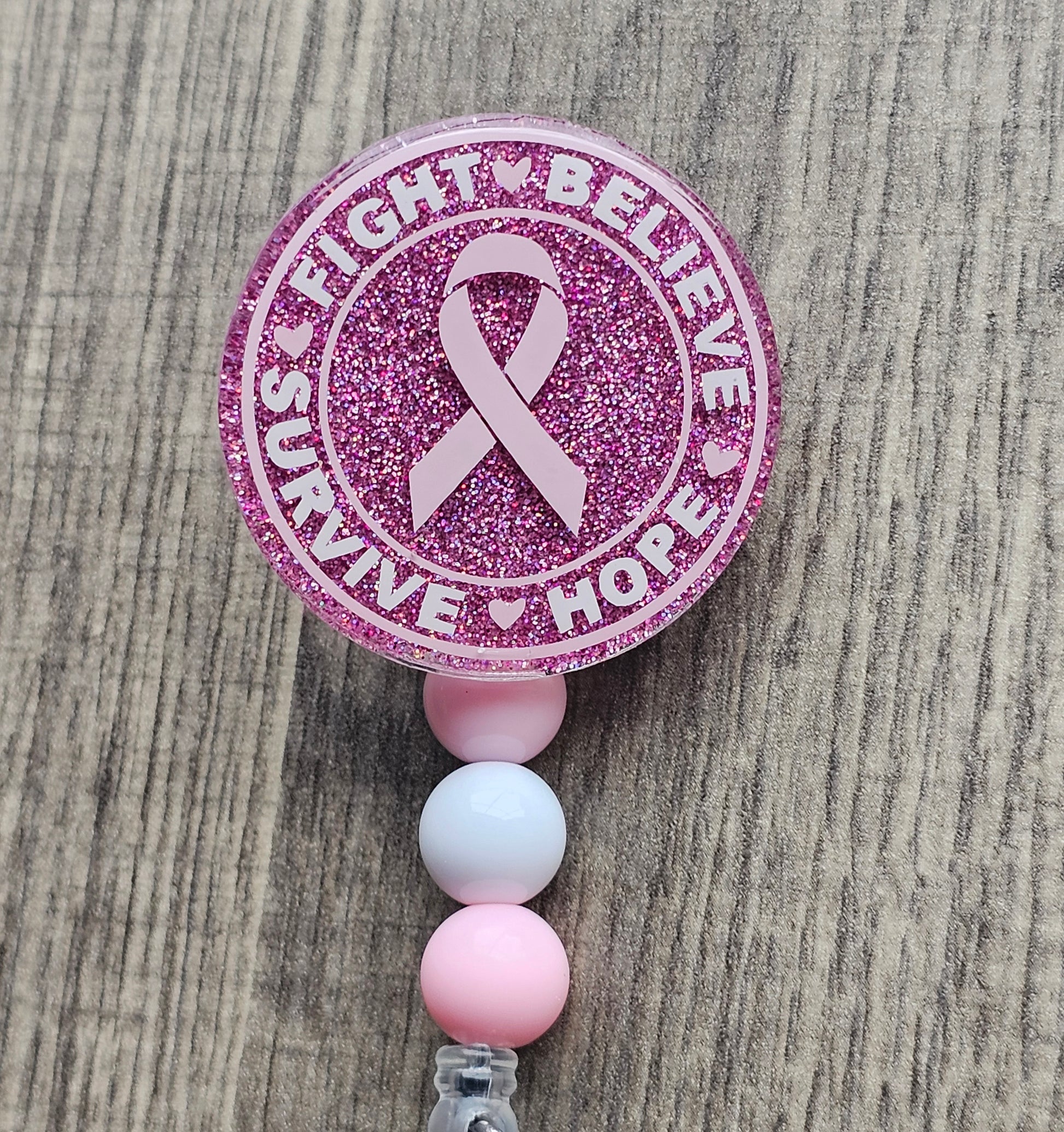 a pink badge reel stating fight, believe, survive hope, along with a breast cancer awareness symbol in the middle in bringing awareness to breast cancer awareness month