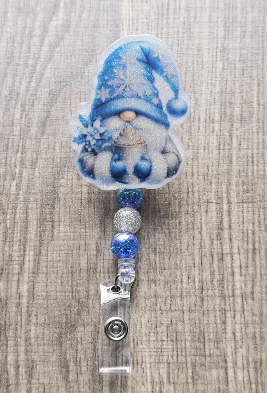 A badge reel shaped like an adorable gnome, this badge reel features a cozy gnome bundled up in a festive sweater, gloves, and a hat, holding a steaming cup of hot chocolate.