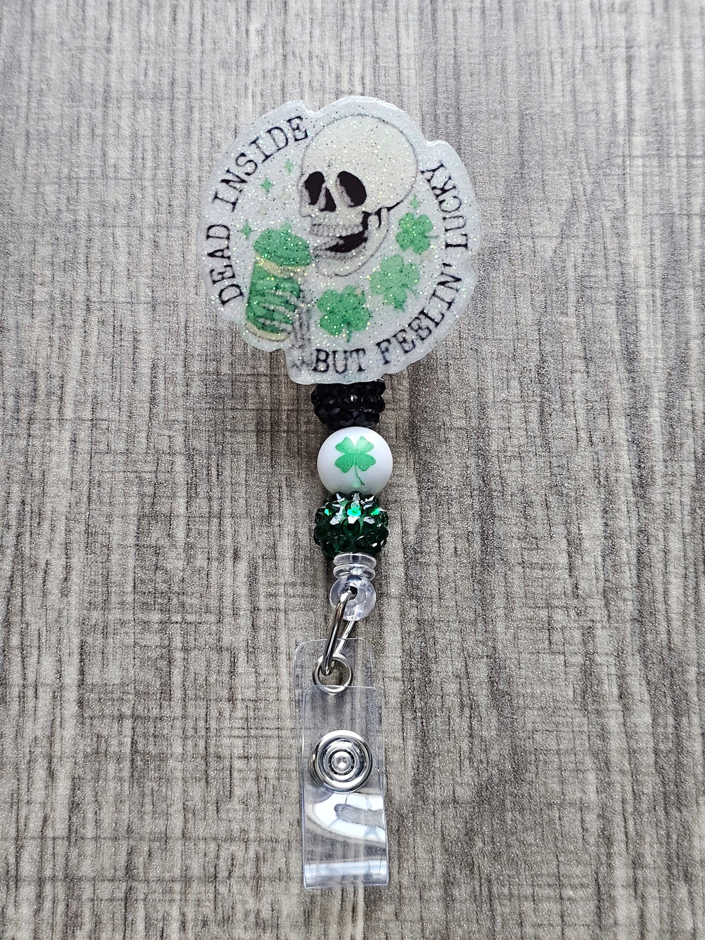 a badge reel featuring a skeleton holding a drink with a st. patrick's theme along with the words Dead Inside But Feeling Lucky