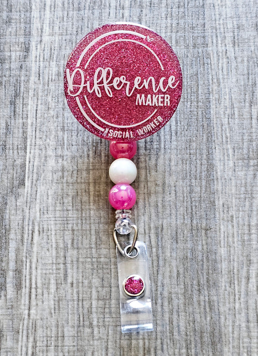 Social work-themed badge reel with "Difference Maker – #SocialWorker" printed on a glittery background, available in multiple colors.