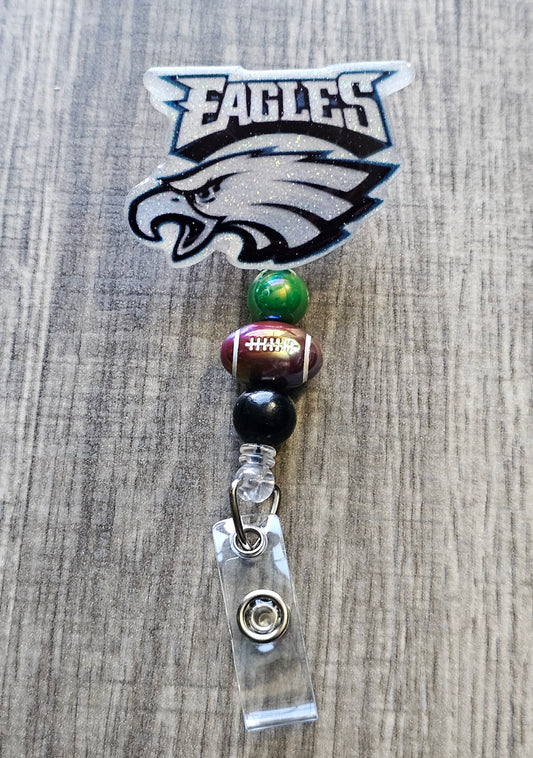 Philadelphia Eagles-inspired bird mascot badge reel with football beads, in glitter acrylic.