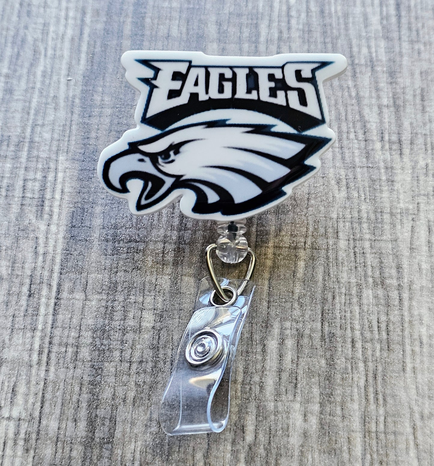 Philadelphia Eagles-inspired bird mascot badge reel with football beads, in white acrylic.