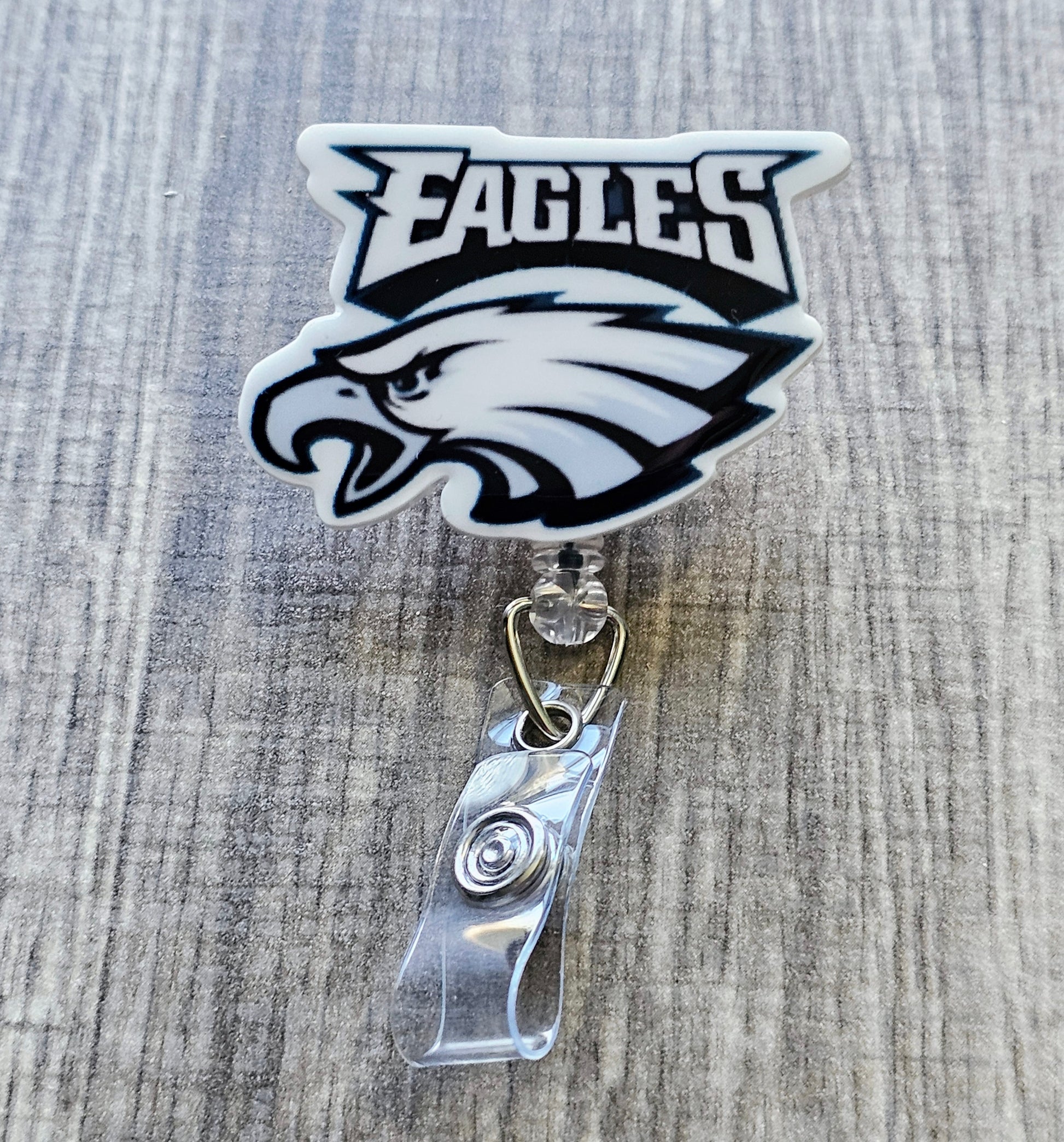 Philadelphia Eagles-inspired bird mascot badge reel with football beads, in white acrylic.
