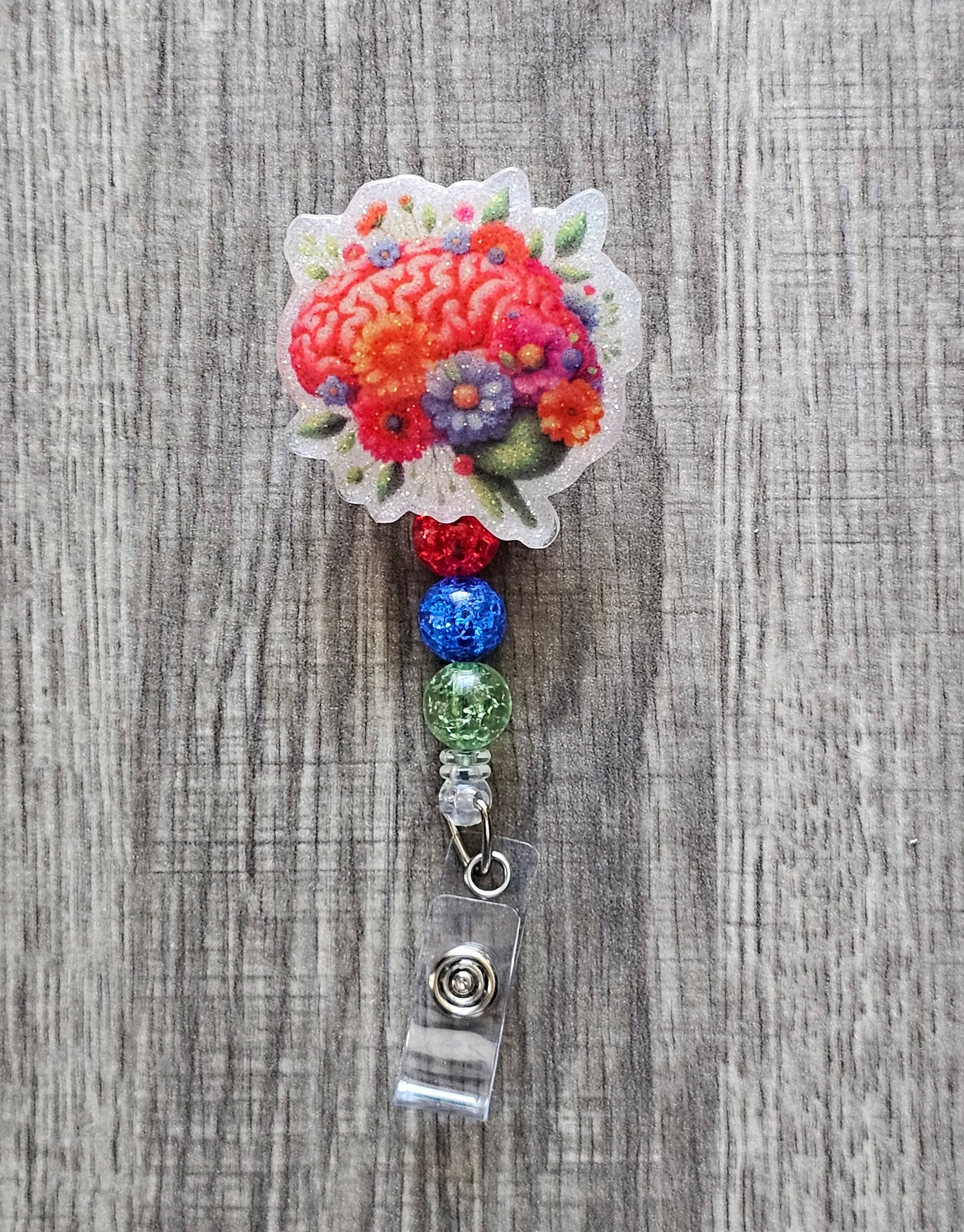 Brain graphic badge reel with flowers and leaves surrounding it, with beads.