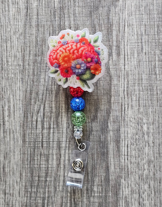 Brain graphic badge reel with flowers and leaves surrounding it, with beads.