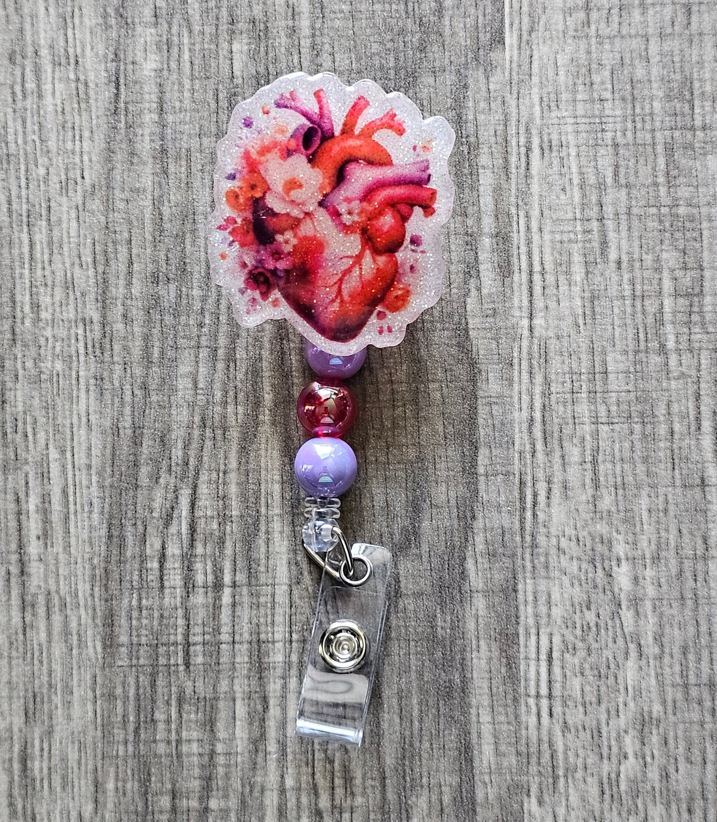 Heart-shaped badge reel with a heart graphic surrounded by flowers and matching beads.
