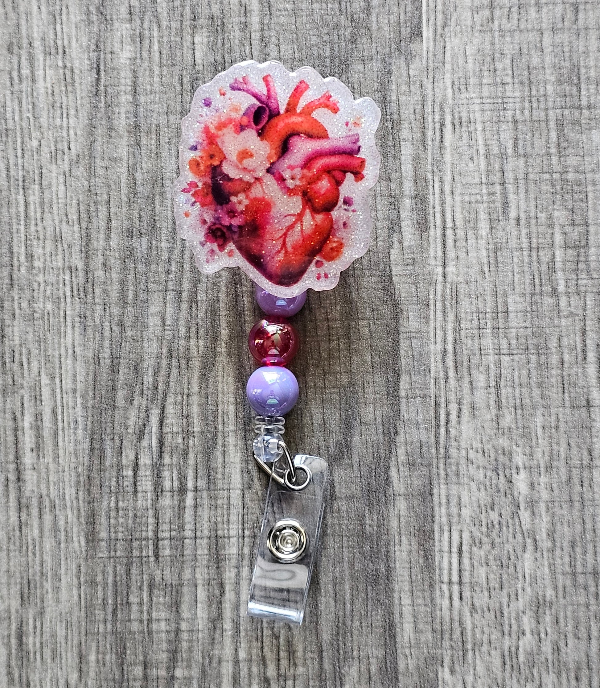Heart-shaped badge reel with a heart graphic surrounded by flowers and matching beads.