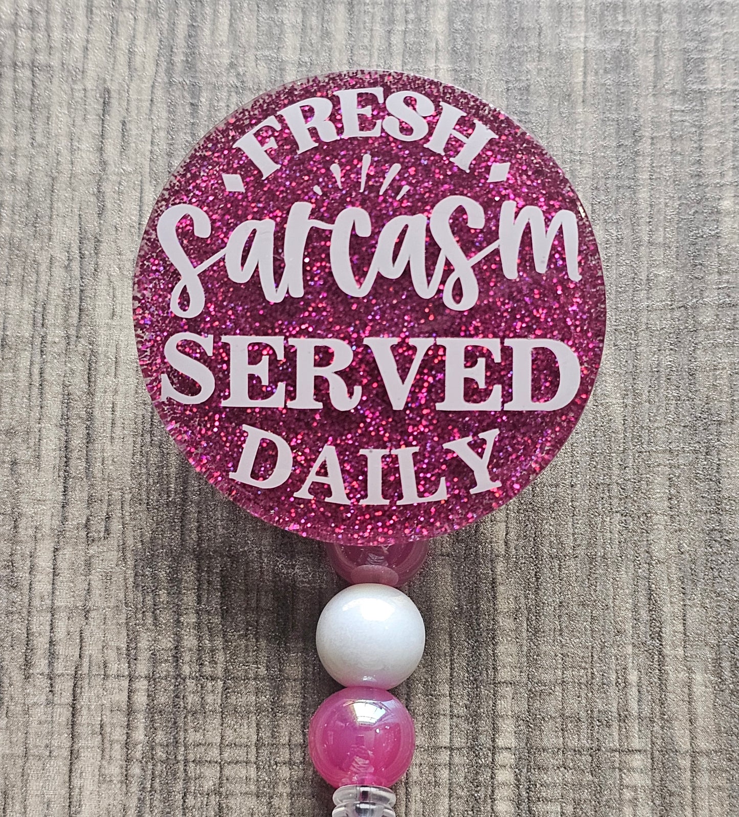 A badge reel stating Fresh Sarcasm Served Daily available in a variety of colors