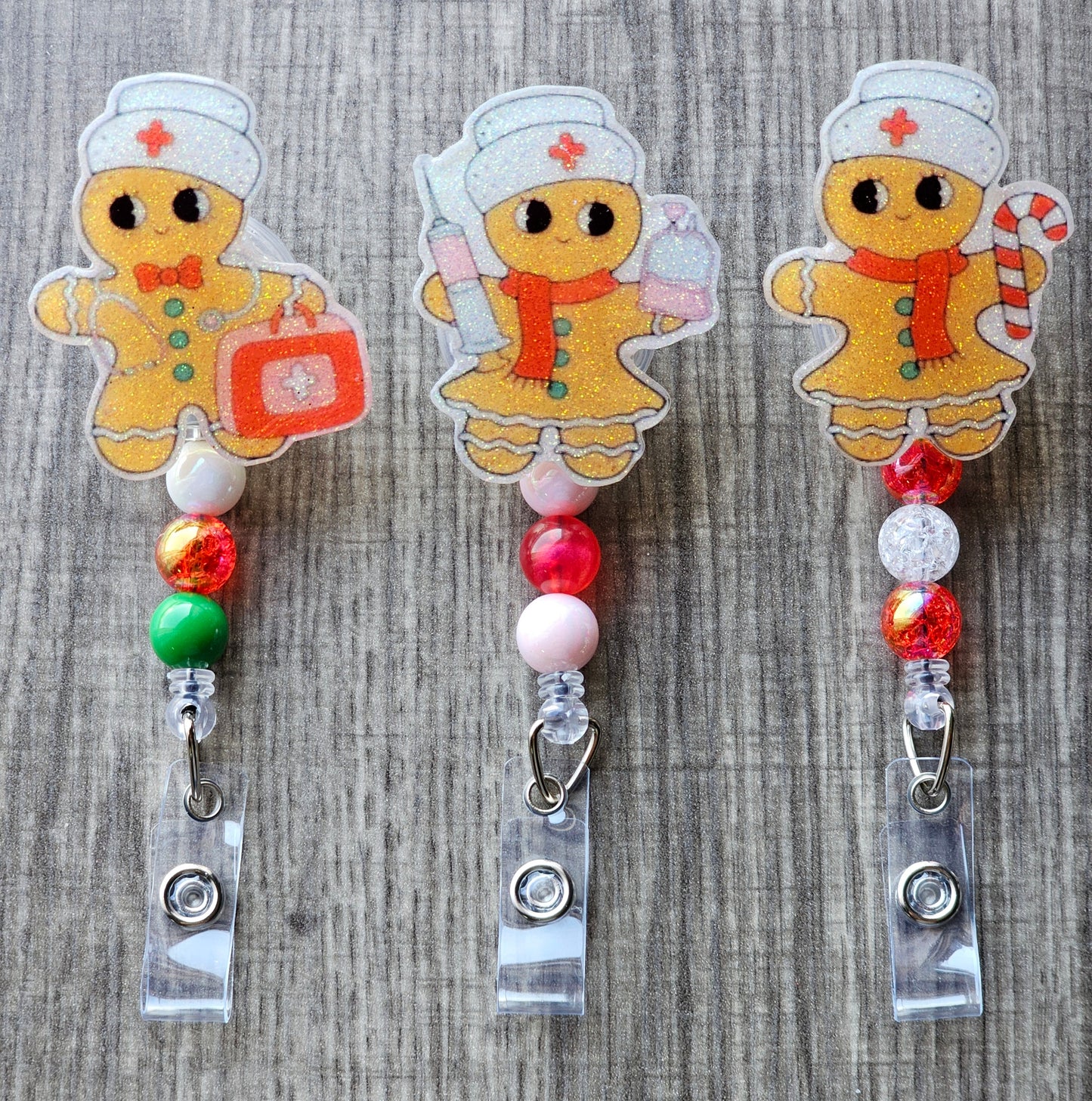 A badge reel collection features three adorable gingerbread nurses, each adorned with a classic nurse hat. One holds a syringe, another carries a first aid kit, and the third holds a festive candy cane.