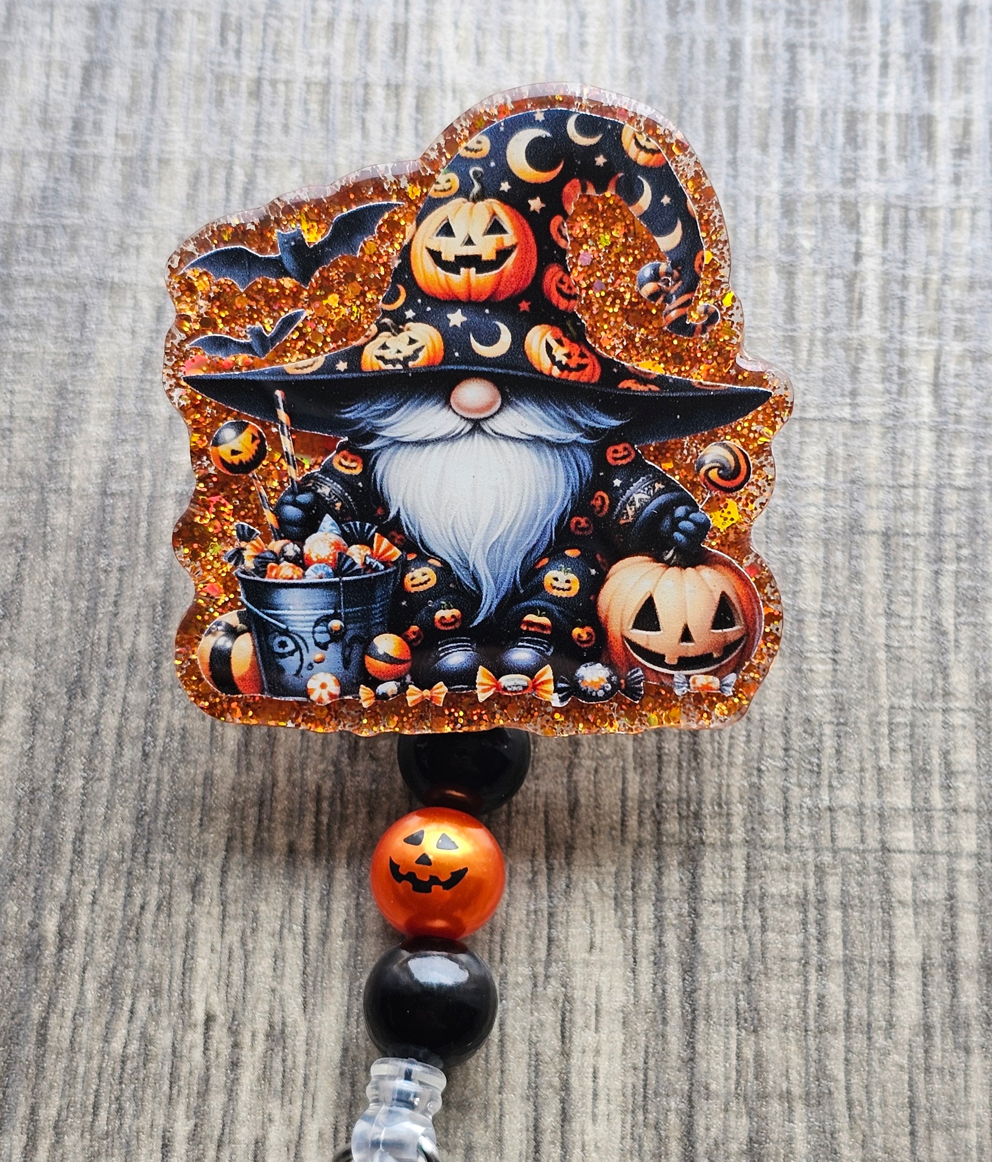 Gnome in a wizard costume adorned with pumpkins beside a trick or treat bucket along with a jack-o-lantern
