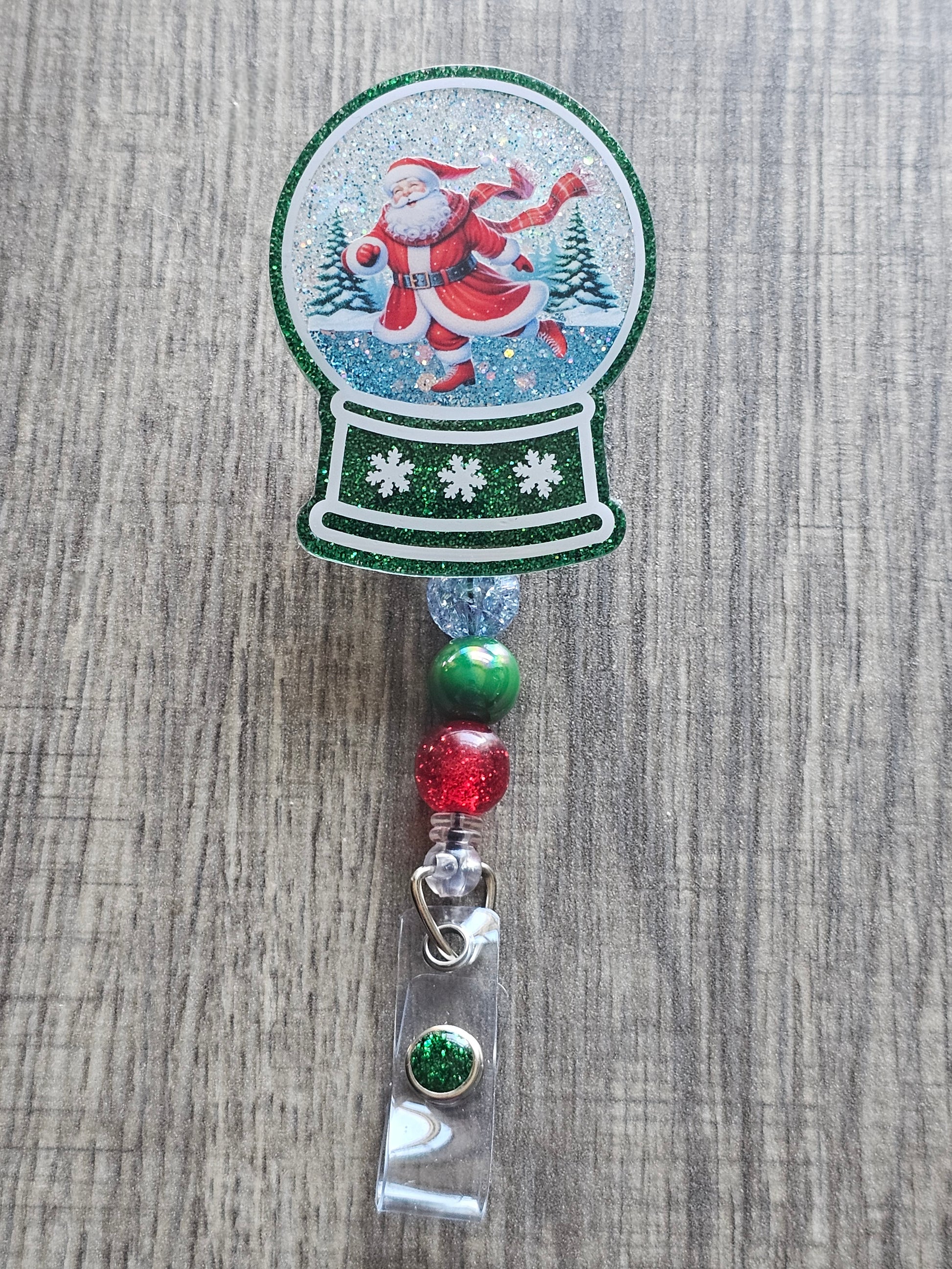A badge reel with a snow globe design featuring Santa skating on Ice.