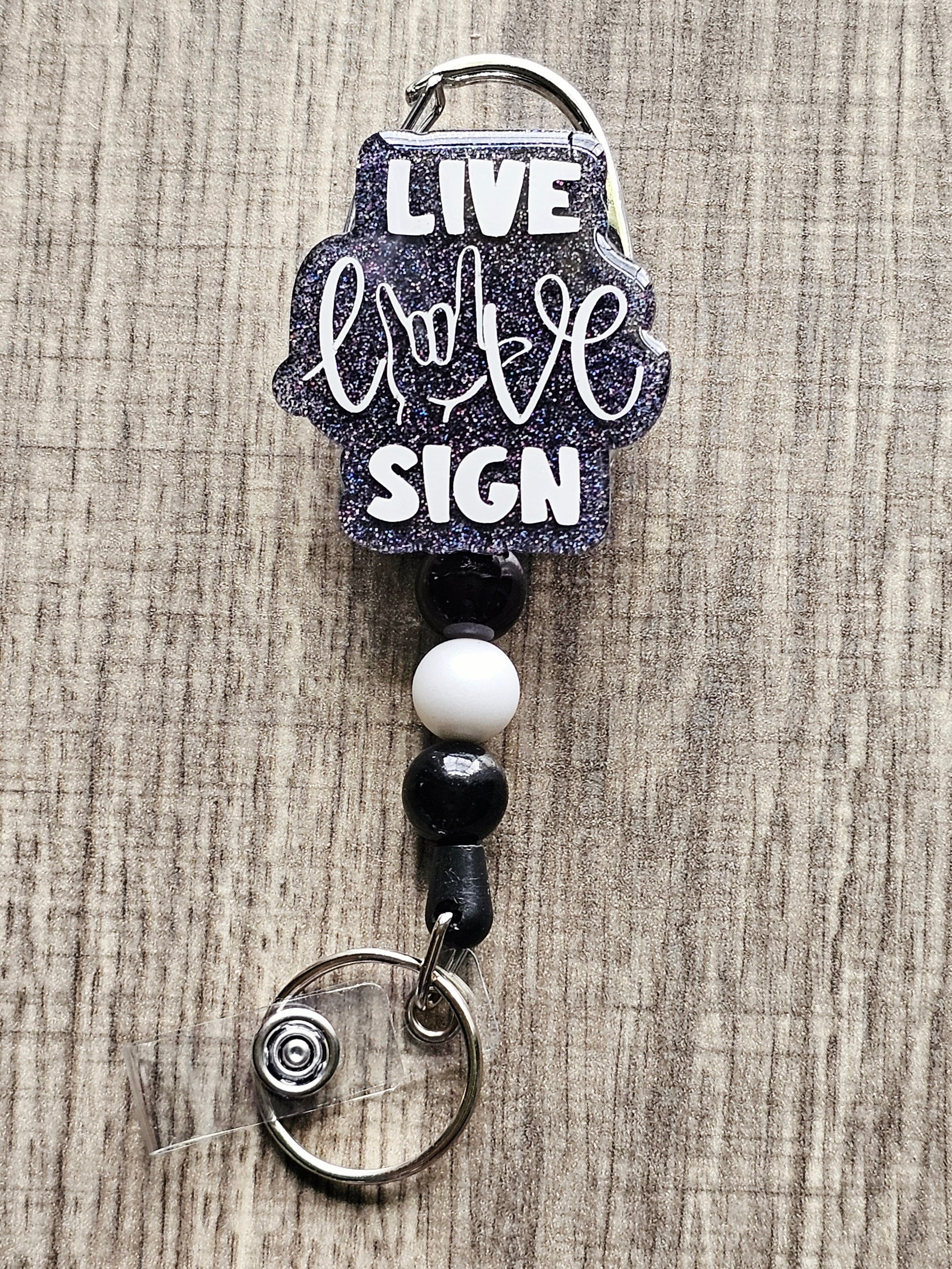 A badge reel with the statement live, love, sign, .