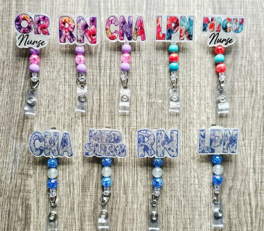 Custom nurse badge reels with floral backgrounds and healthcare titles like RN, CNA, and LPN.
