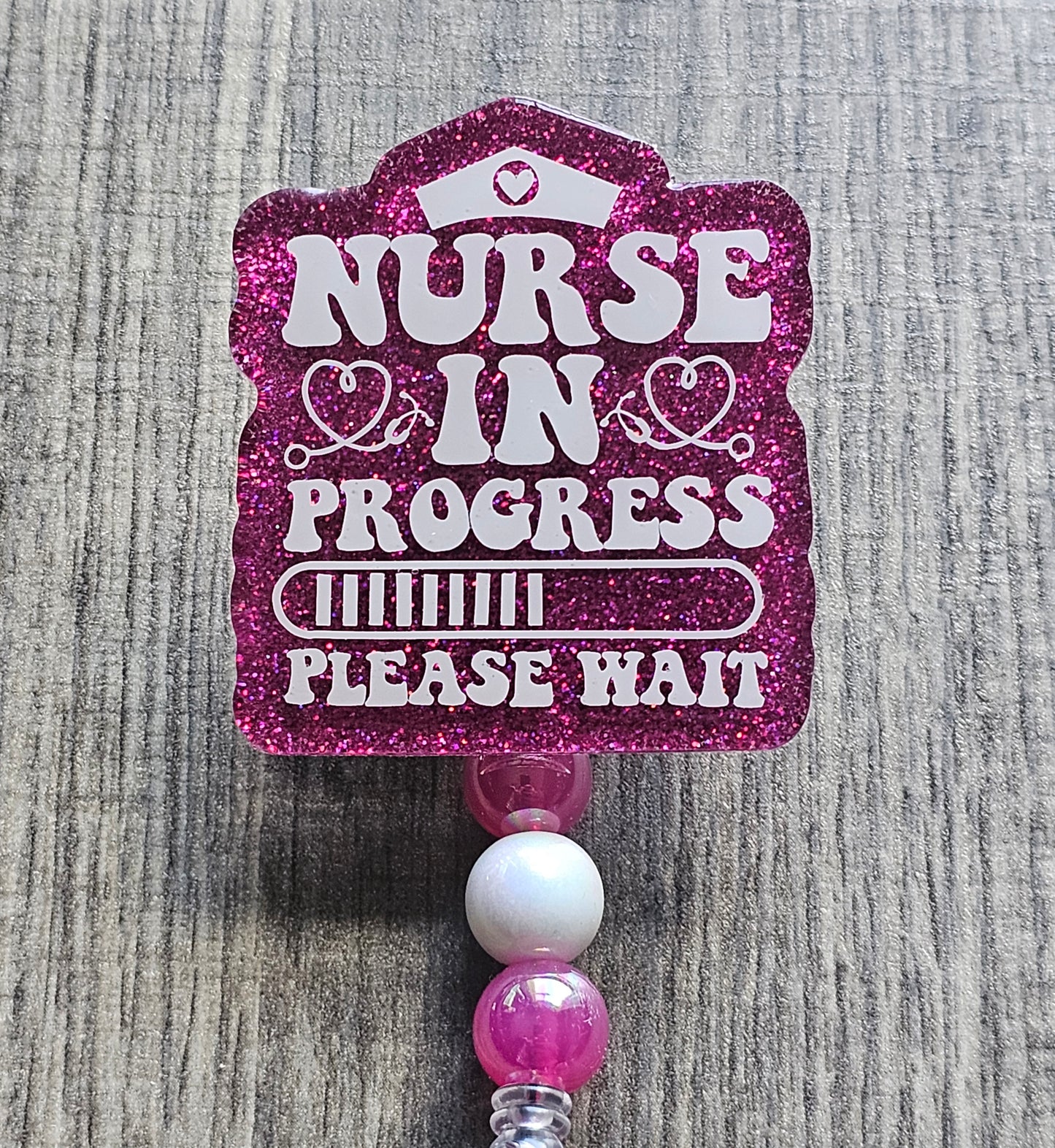 a badge reel stating Nurse In Progress Please Wait along with the a loading bar incorporated in the design which can also be available in multiple colors