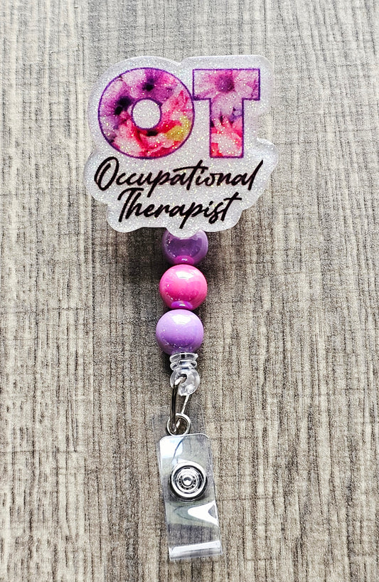 Alt Text: Floral OT Occupational Therapist badge reel with white glitter background and retractable cord.