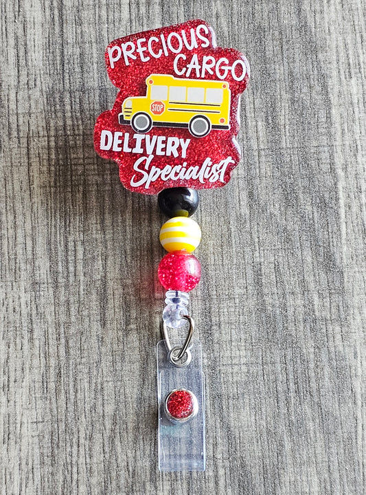 A badge reel that features a school bus surrounded by the statement Precious Cargo Delivery Specialist