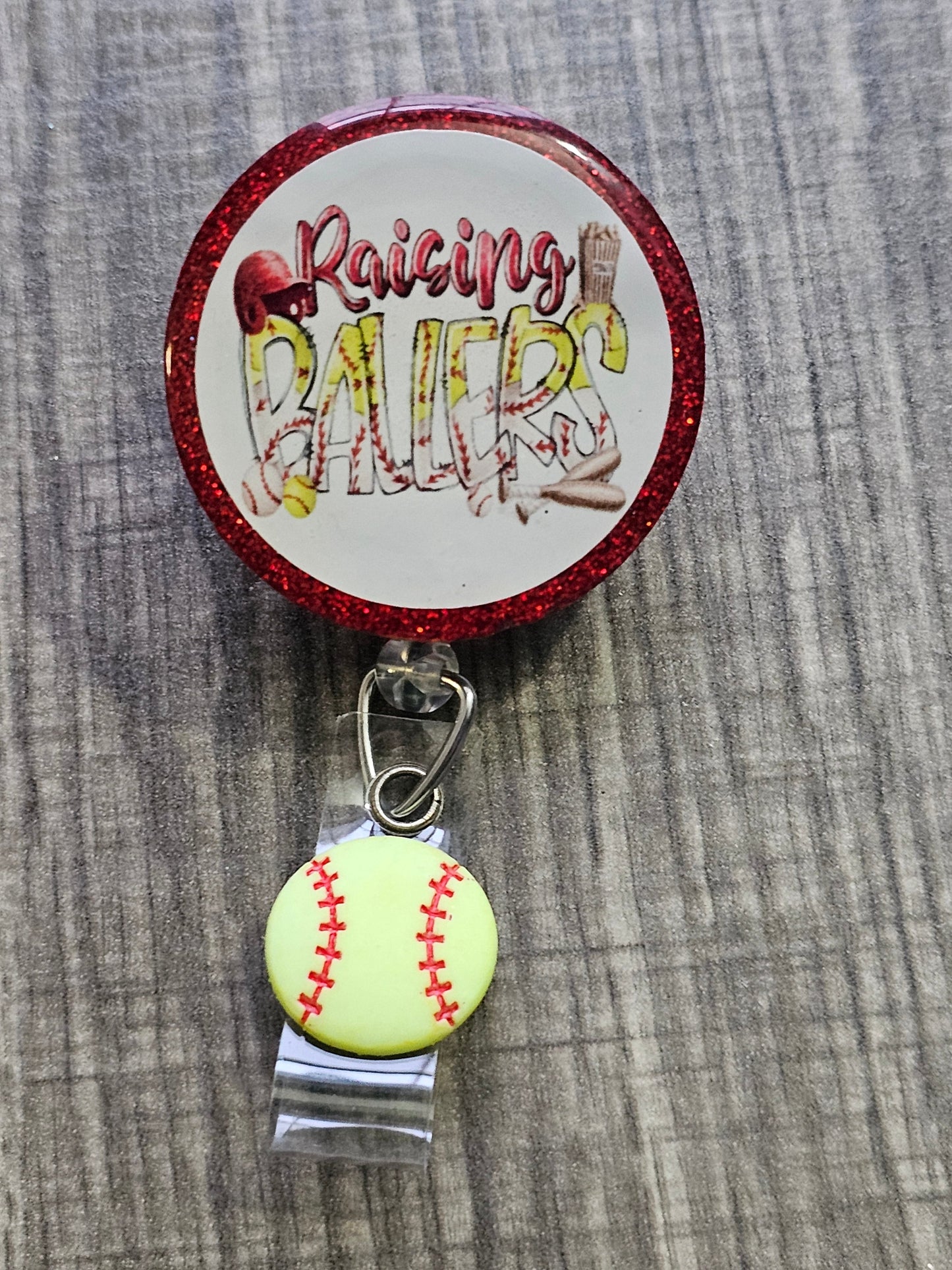 A Badge Reel with the statement Raising Ballers with a softball clip .