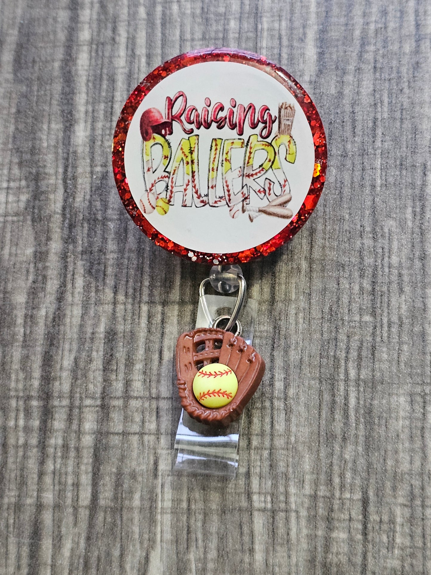 A Badge Reel with the statement Raising Ballers with a catchers glove catching a ball