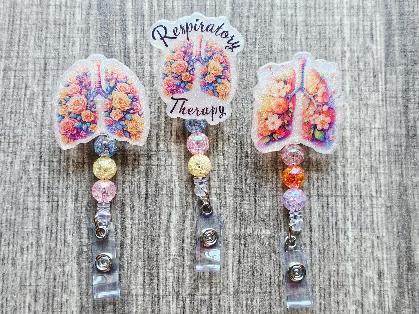 A collection of three respiratory therapy badge reels featuring floral lungs and respiratory system designs.