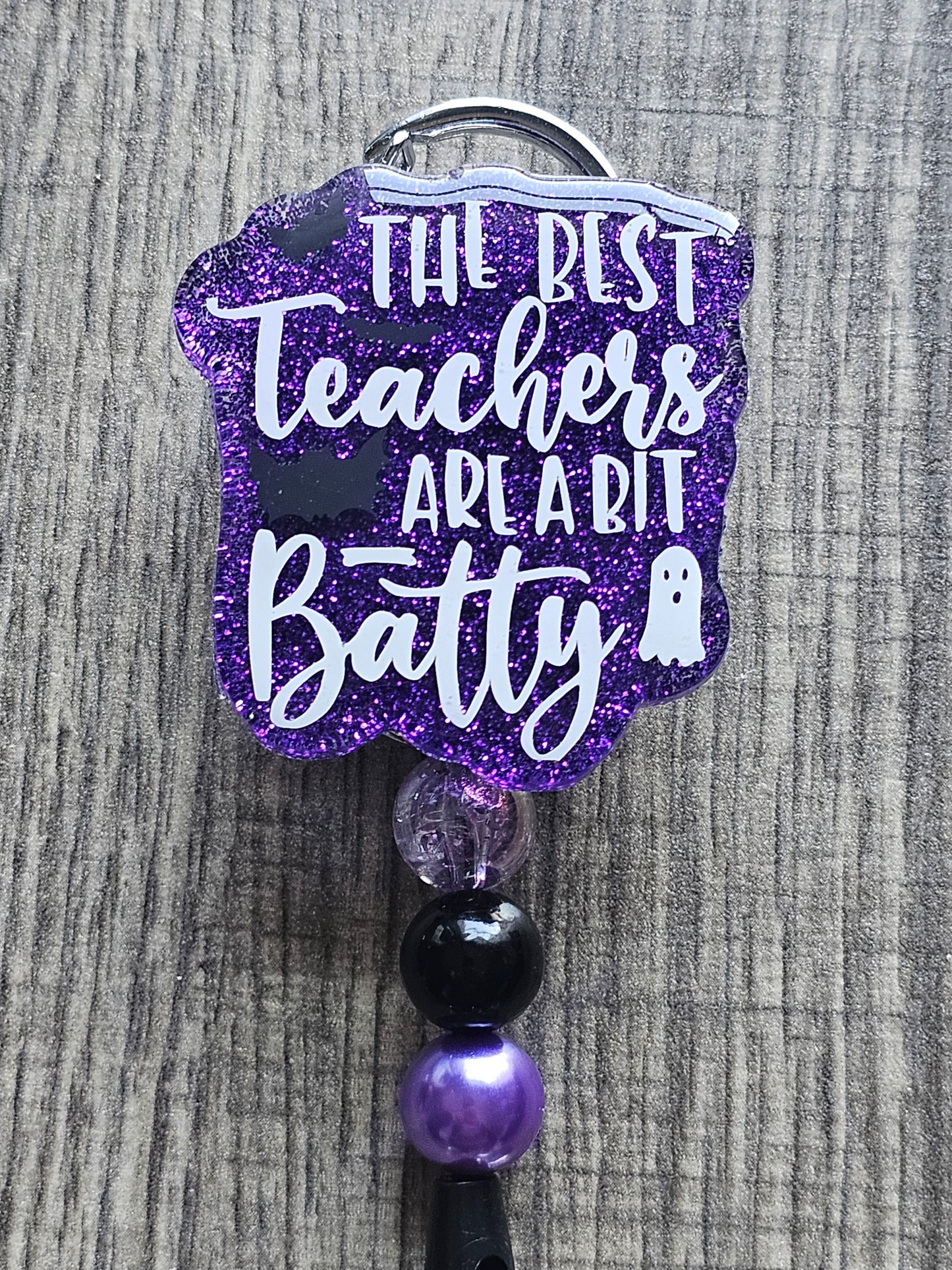 a badge reel stating the best teachers are a bit batty which incorporates bats and a ghost in the design
