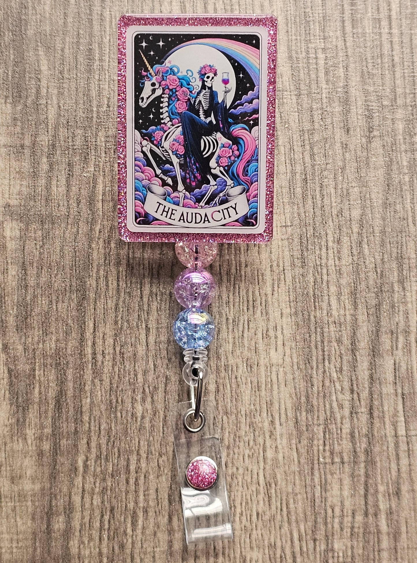 Badge Reel Shaped as a Tarot card featuring a skeleton witch riding a skeleton horse with a glass of wine with the moon in the background, titled The Audacity