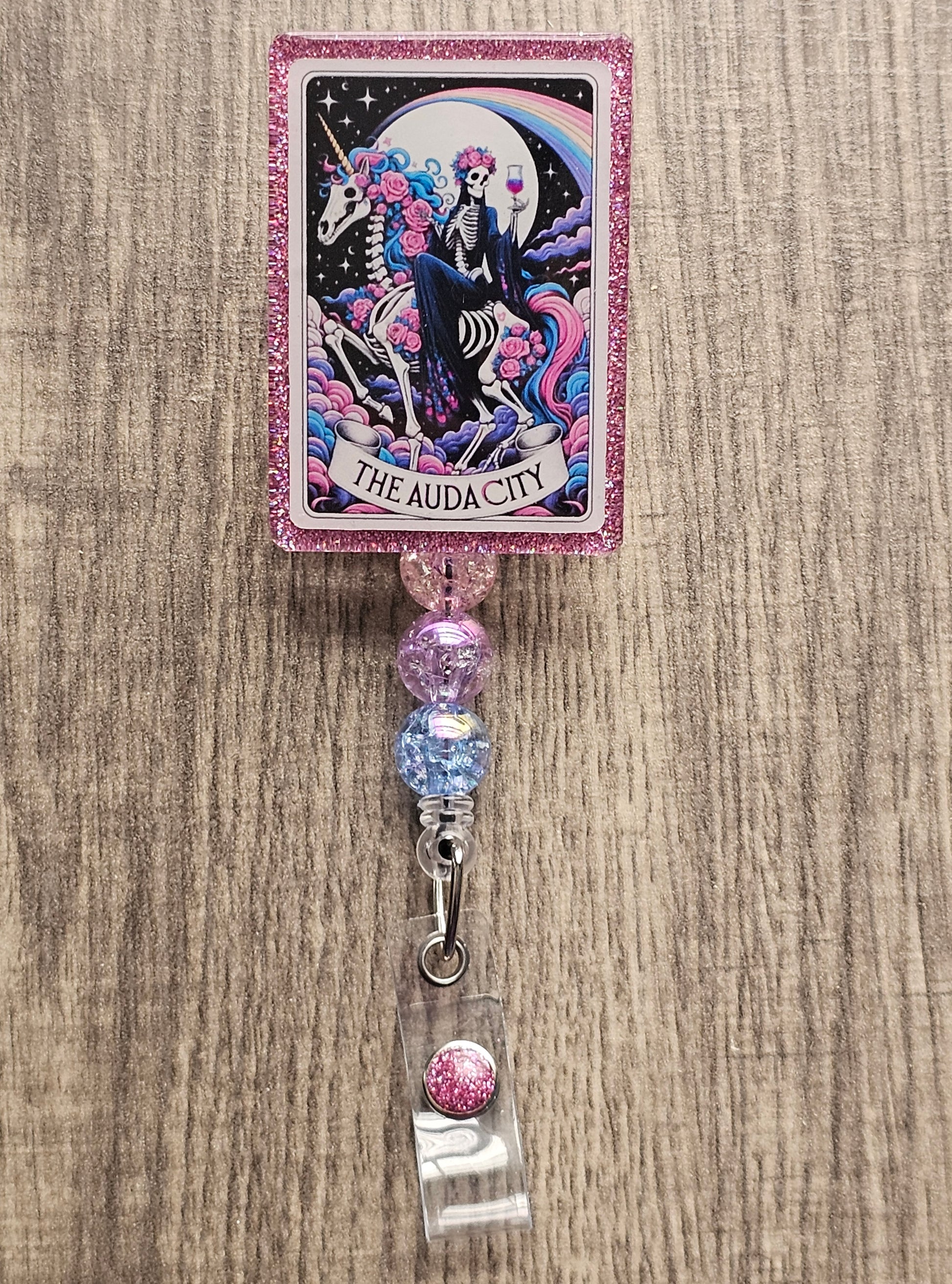 Badge Reel Shaped as a Tarot card featuring a skeleton witch riding a skeleton horse with a glass of wine with the moon in the background, titled The Audacity
