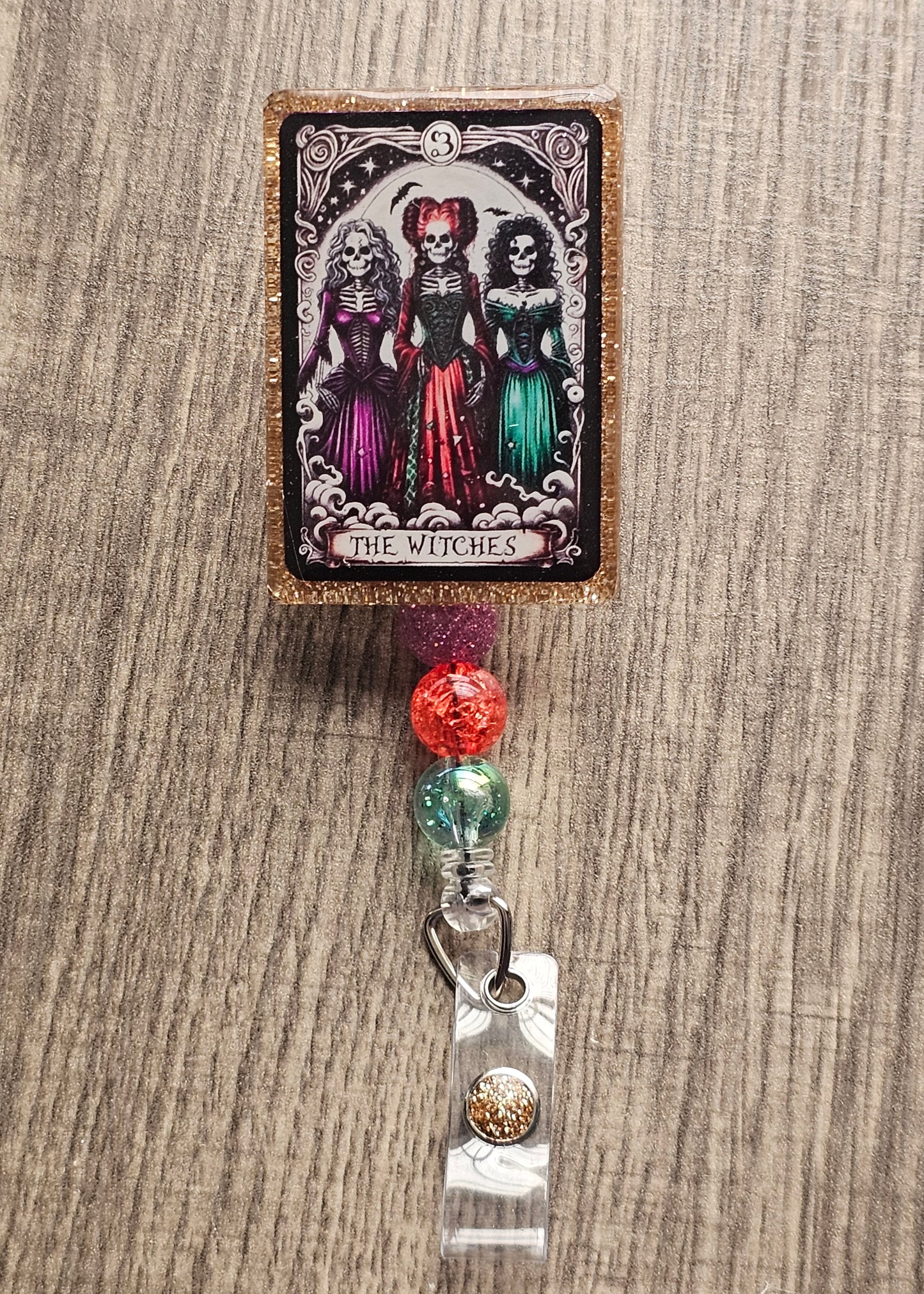 Badge Reel shaped as a Tarot Card featuring three witches