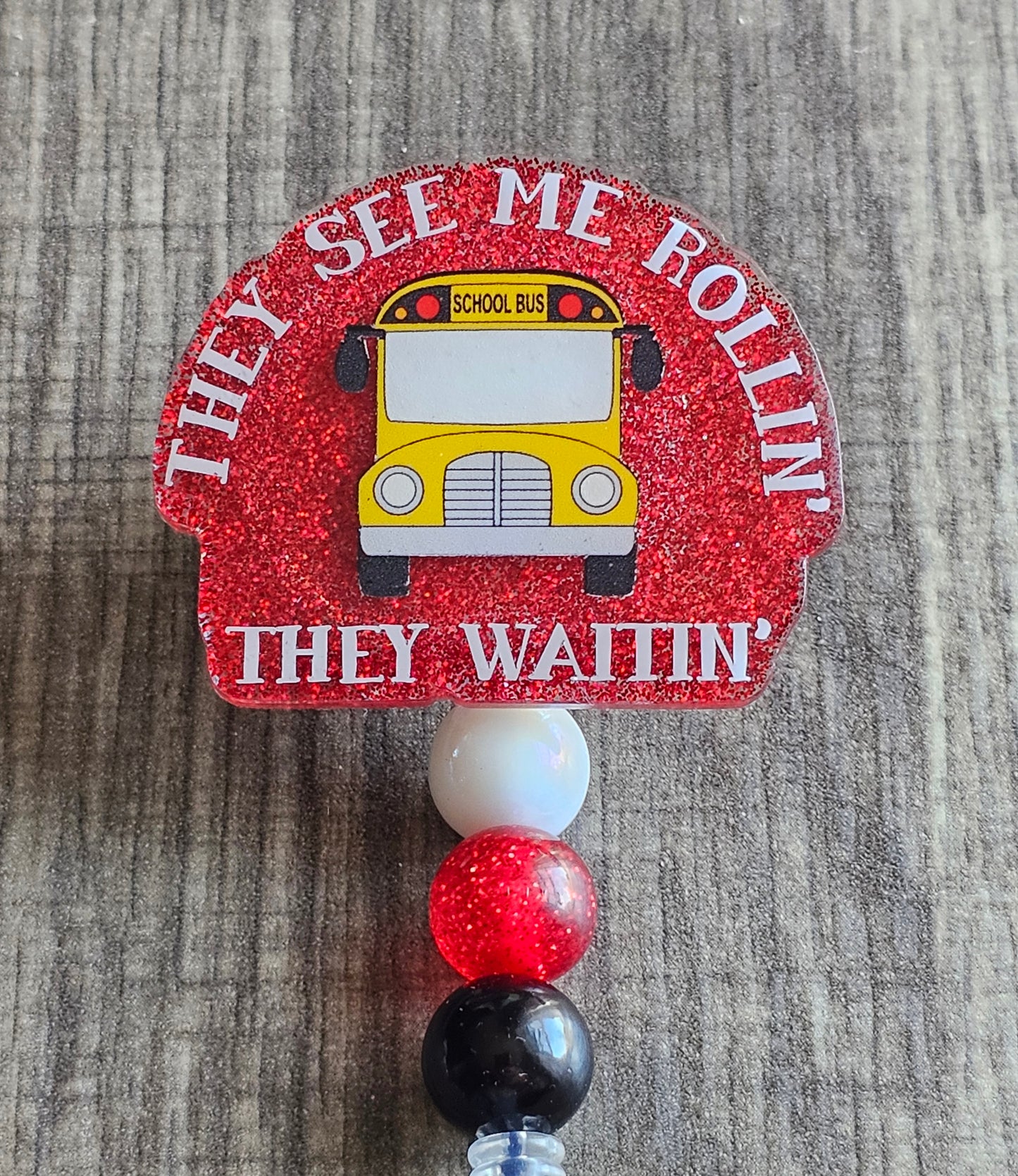 A badge reel that features a school bus surrounded by the statement They see me rolling, They waiting