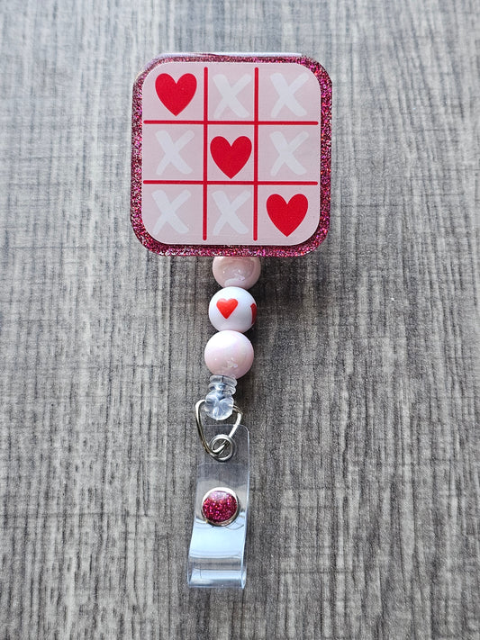 A badge reel featuring a tic-tac toe board where hearts win in honor of valentine's day