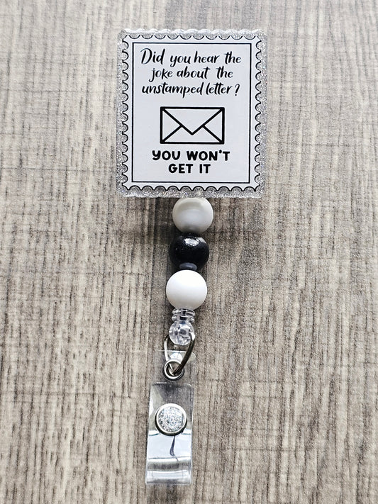 Stamp-shaped badge reel with a mail joke that says “Did you hear the joke about the unstamped letter? You won’t get it.