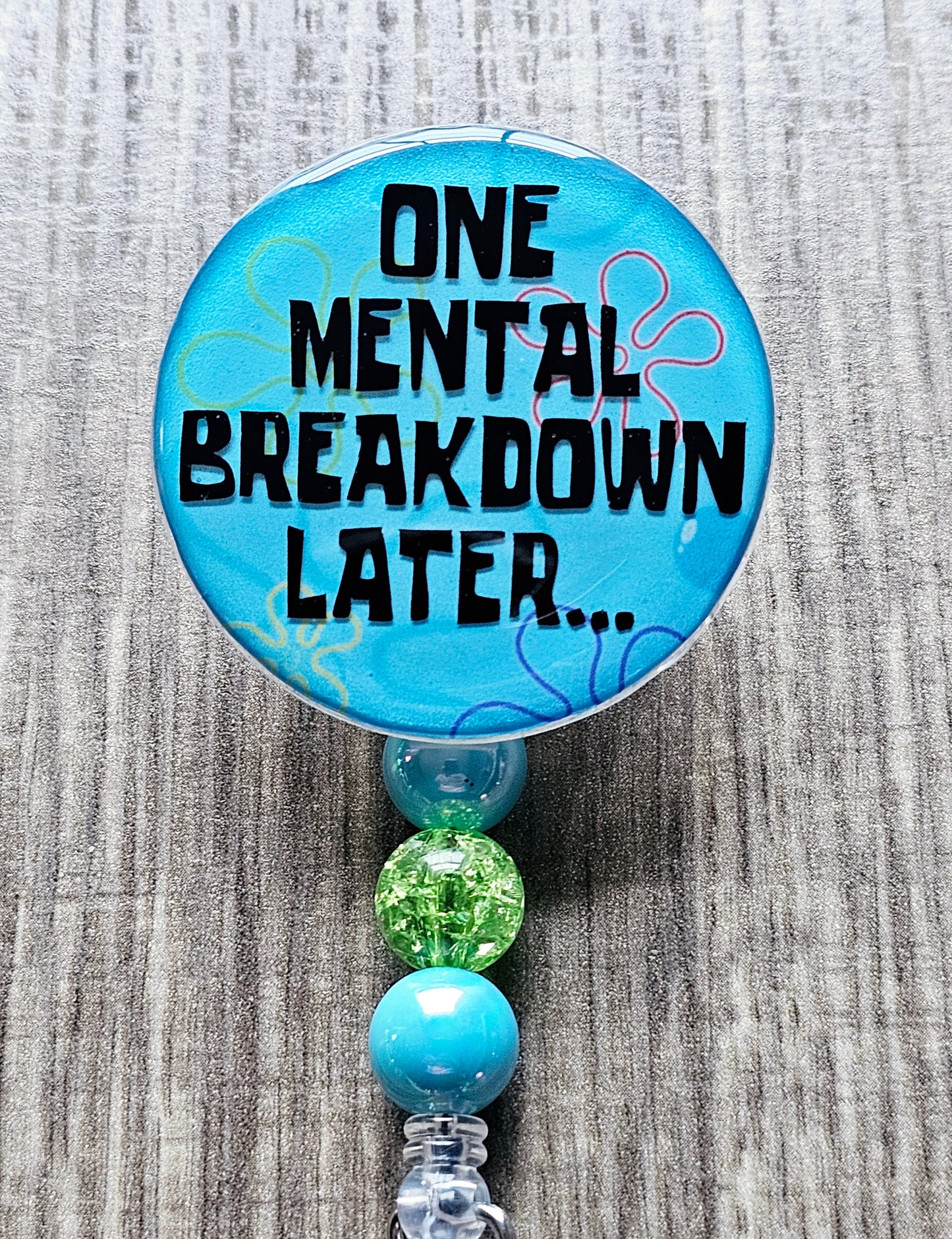 A badge reel with a bold, cartoon-inspired background featuring the phrase “One Mental Breakdown Later...” in a humorous design.