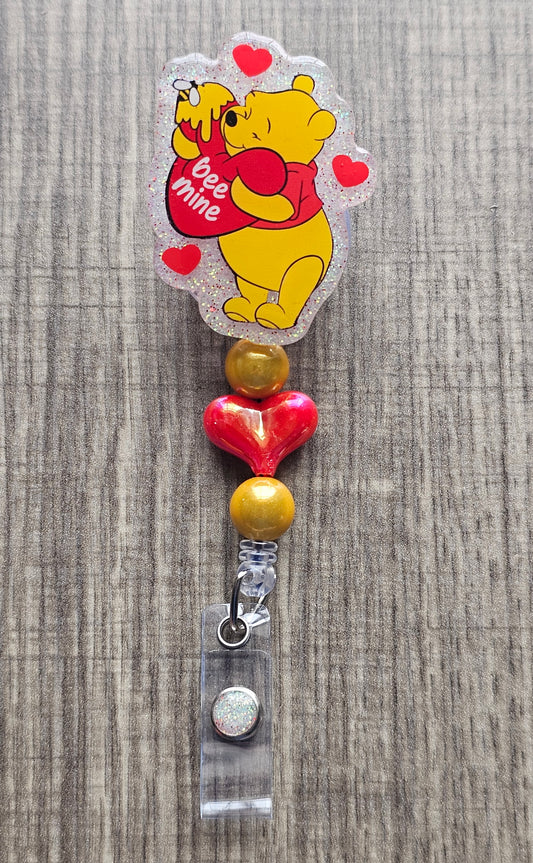 Retractable badge reel with Winnie the Pooh hugging a heart that says Bee Mine with honey drips.