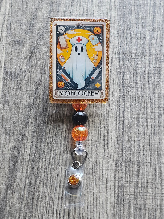 A badge reel that displays a ghost nurse with a nurse hat, along with syringes , clip boards and other nursing accessories in the design of a tarot card.