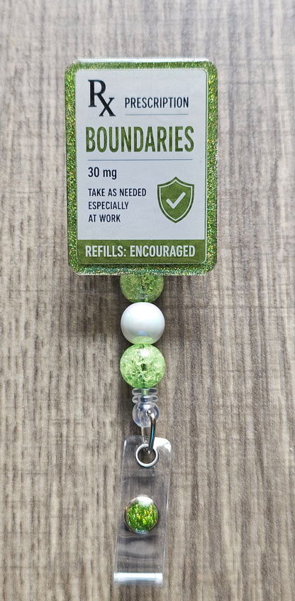 A prescription-style badge reel holder with a green glitter border card that reads 'Rx Prescription Boundaries 30 mg' and a beaded drop with clear and green beads on a wood surface.