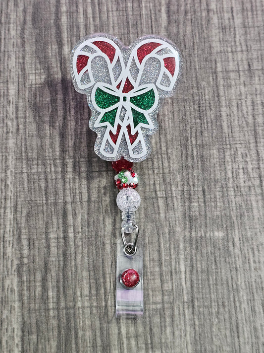 A badge reel featuring two candy canes with Christmas colors crossing each other with a bow linking them together along with a green bow.