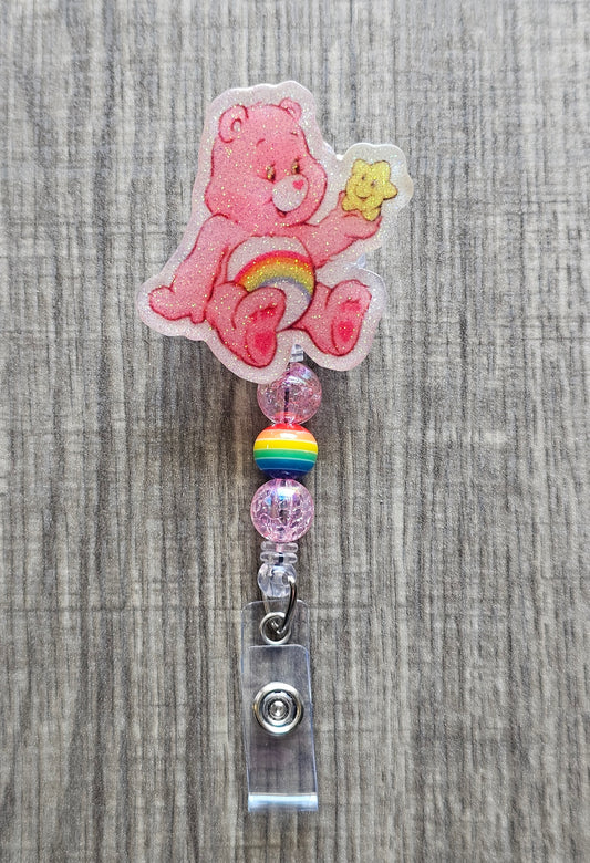 Cheer Care Bear holding a star badge reel with matching pink beads,  with a central rainbow bead, and retractable cord.