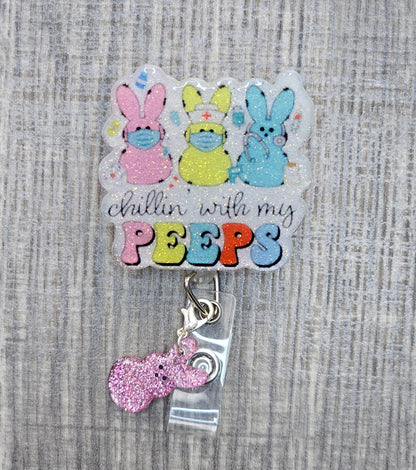 A badge reel featuring three Easter bunnies in nurse decor with the phrase "Chillin’ with My Peeps" and a pink clip attachment.