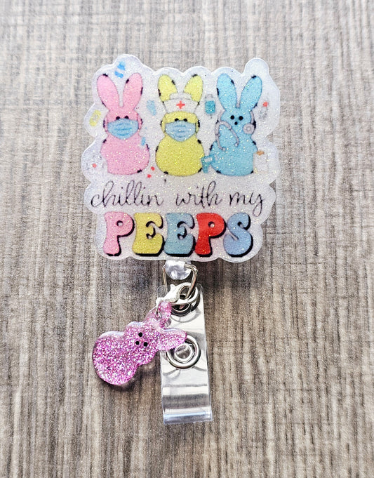 A badge reel featuring three Easter bunnies in nurse decor with the phrase "Chillin’ with My Peeps" and a pink clip attachment.