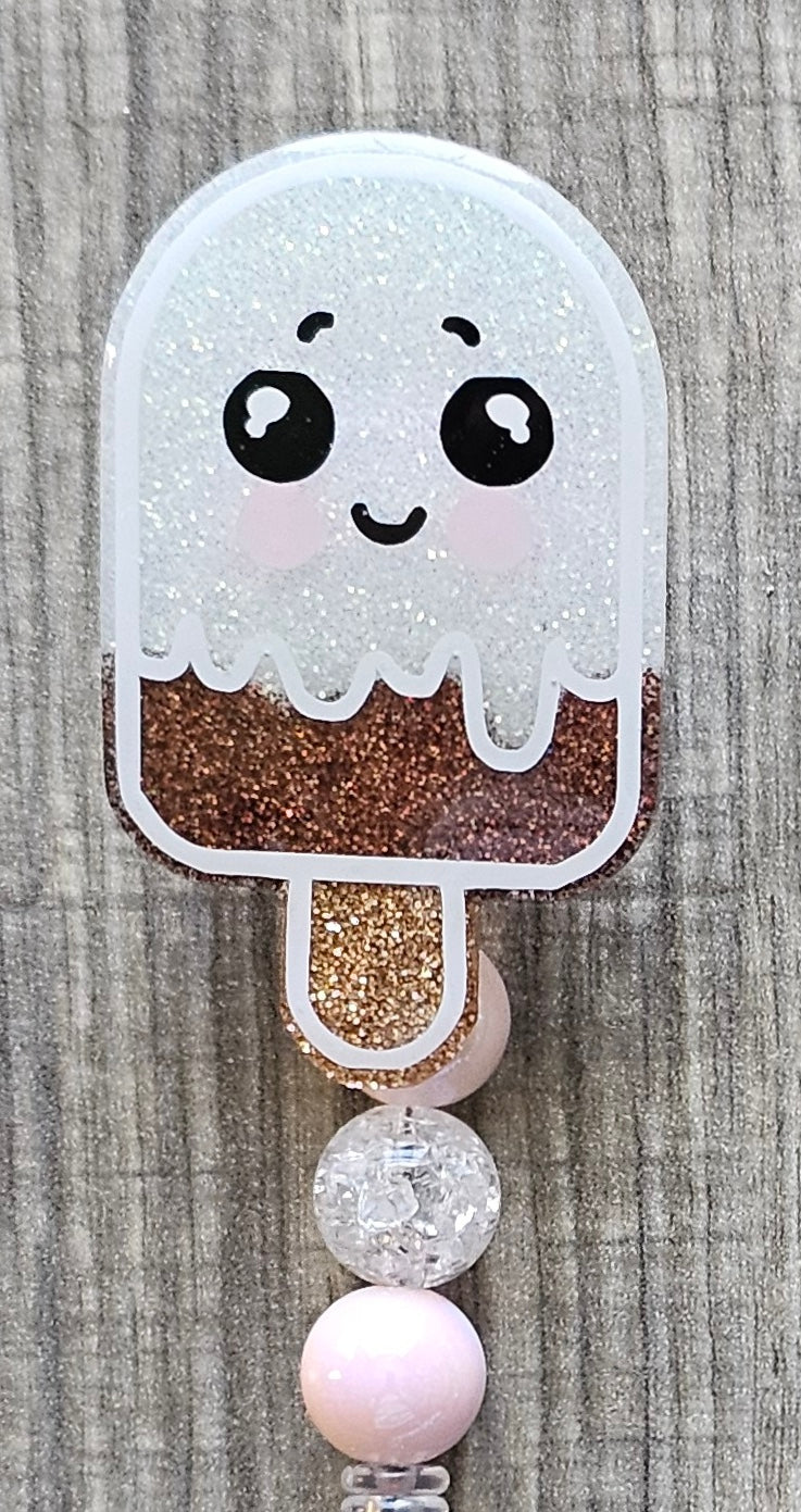 Glittery chocolate vanilla ice cream popsicle charm with beads on a wooden background