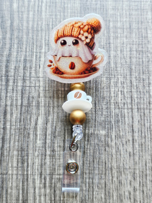 Adorable ghost in a coffee cup with a fall hat on a retractable badge reel with coffee and gold beads.