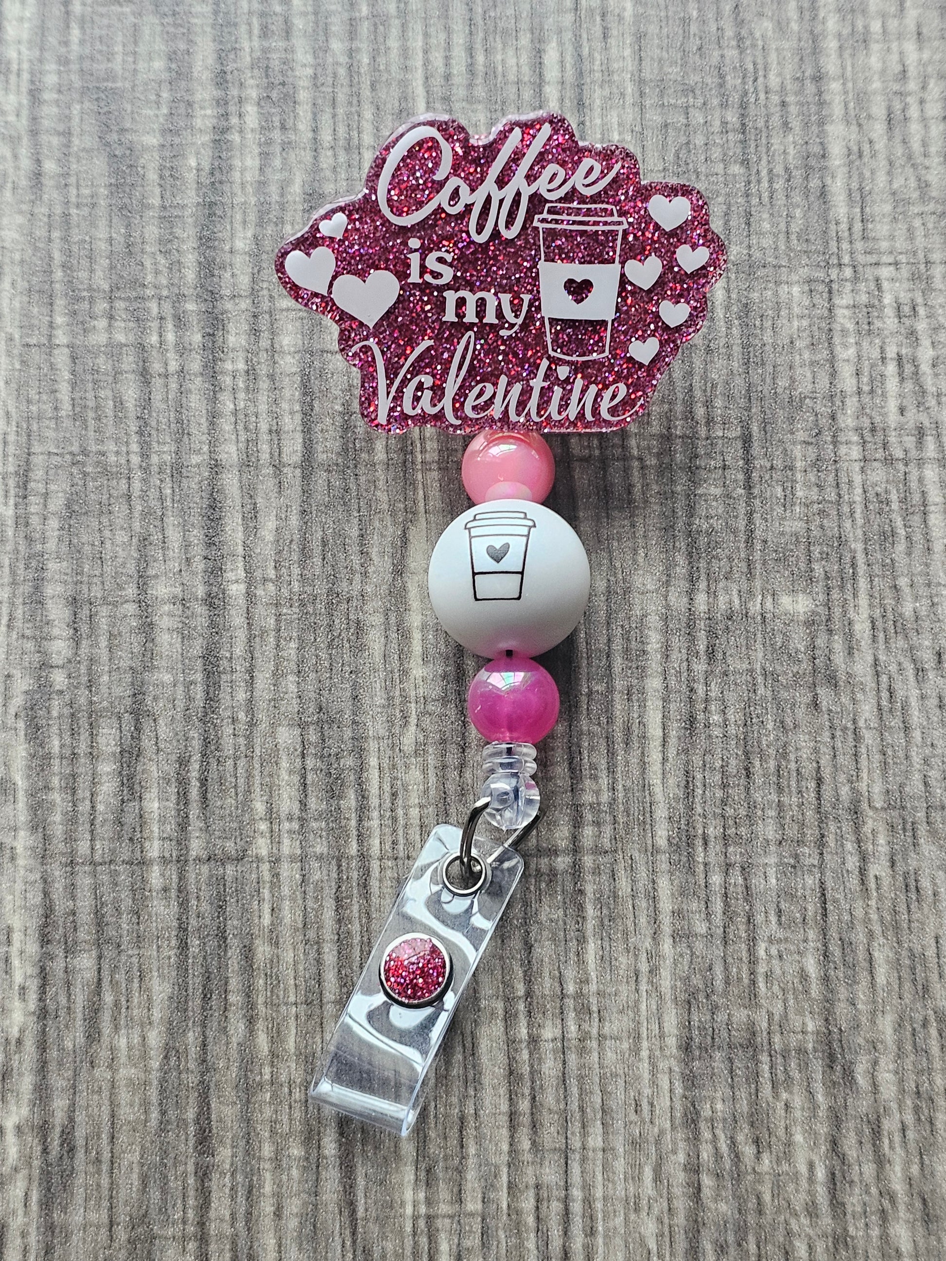 A badge Reel stating Coffee is my valentine featuring a coffee cup along with some hearts surround the badge reel 