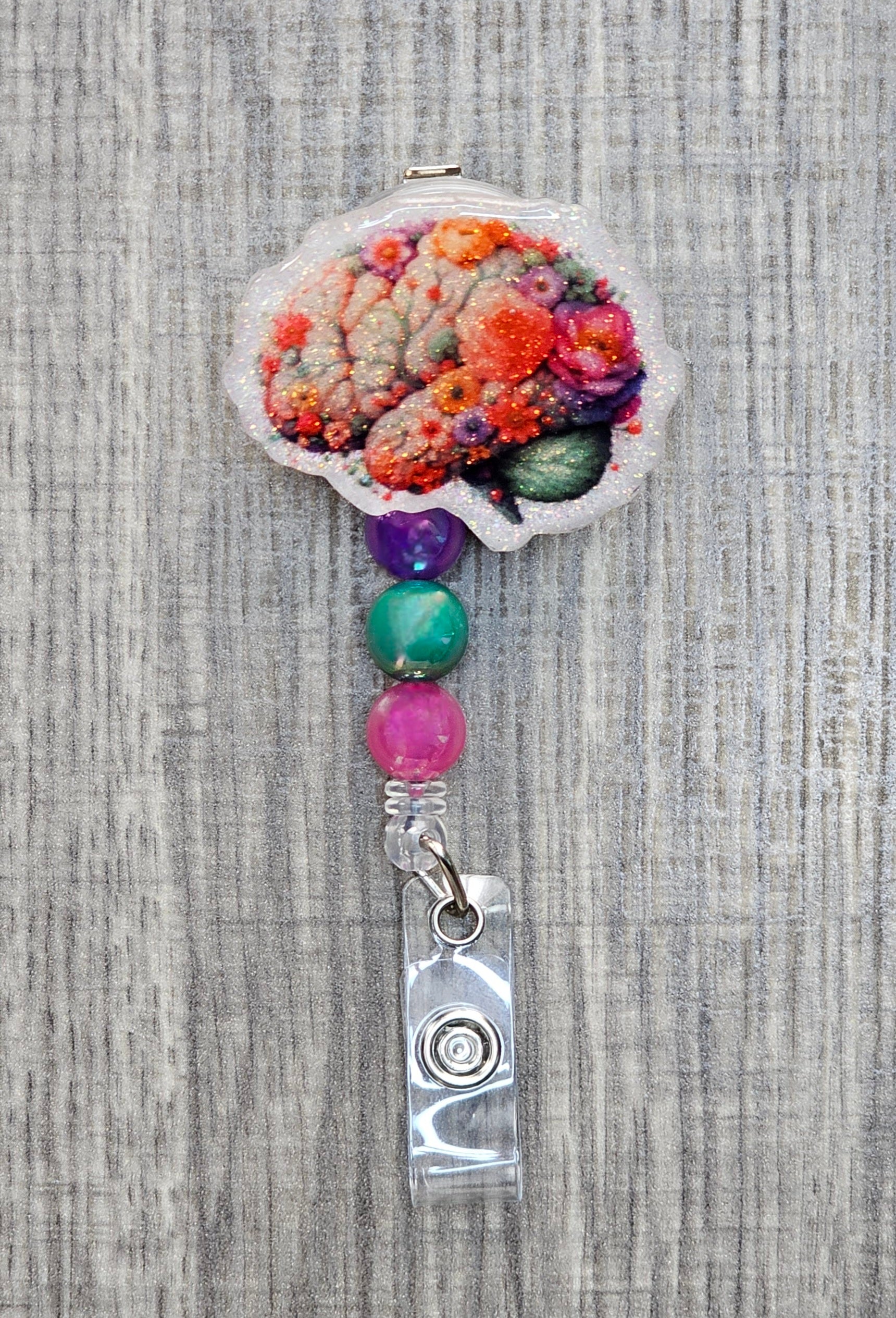 Decorative badge holder with floral brain design and colorful beads on a textured background.
