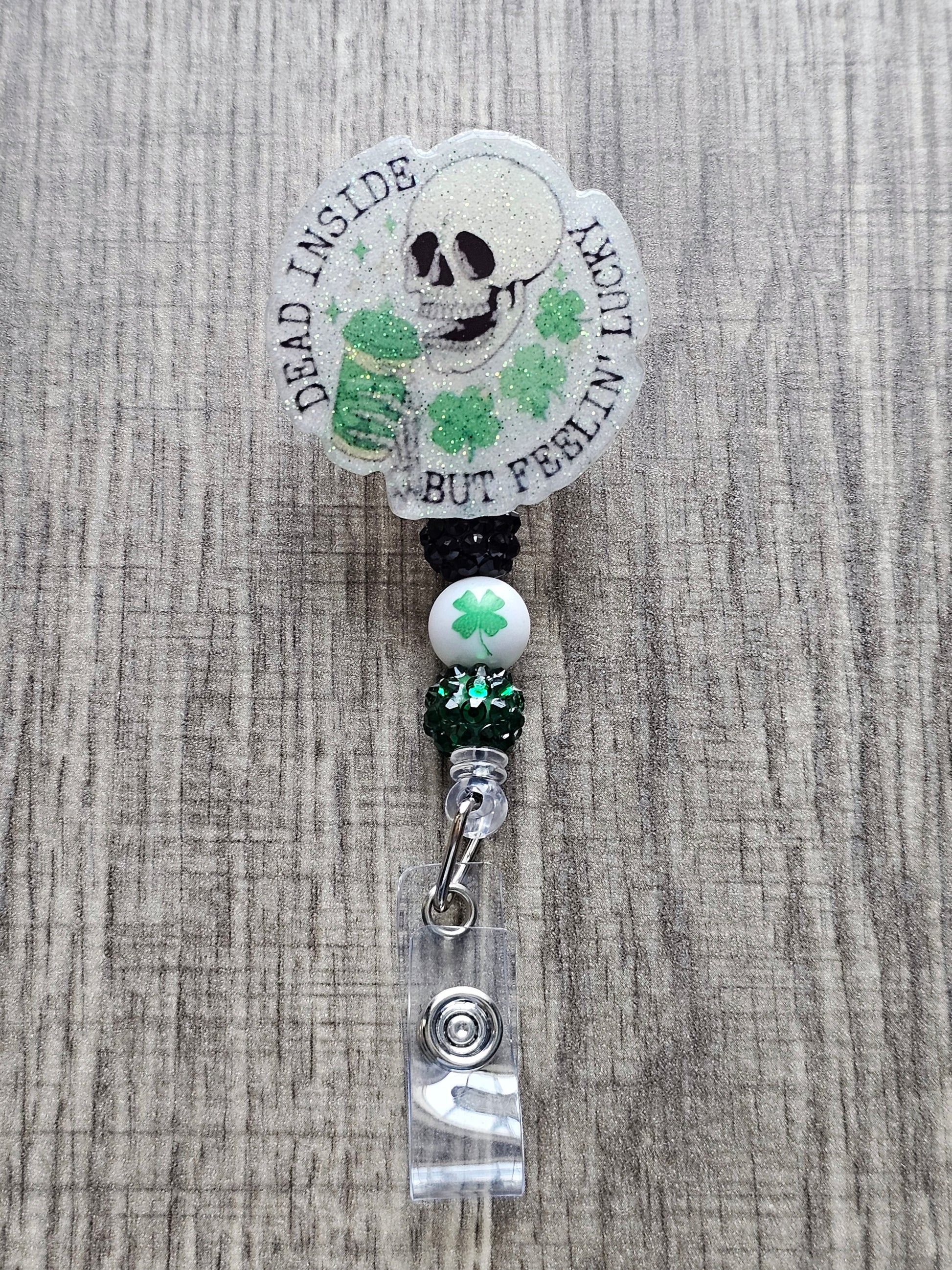 a badge reel featuring a skeleton holding a drink with a st. patrick's theme along with the words Dead Inside But Feeling Lucky 