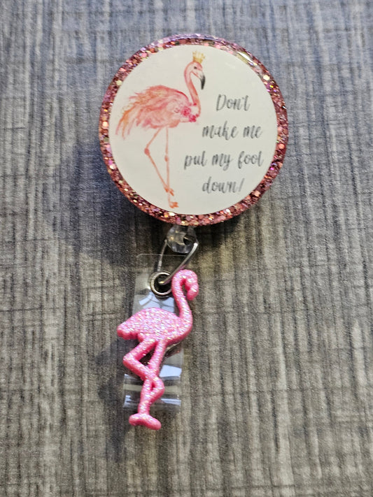 A Badge Reel with a flamingo with its foot up and a crown along with the words don't make me put my foot down.