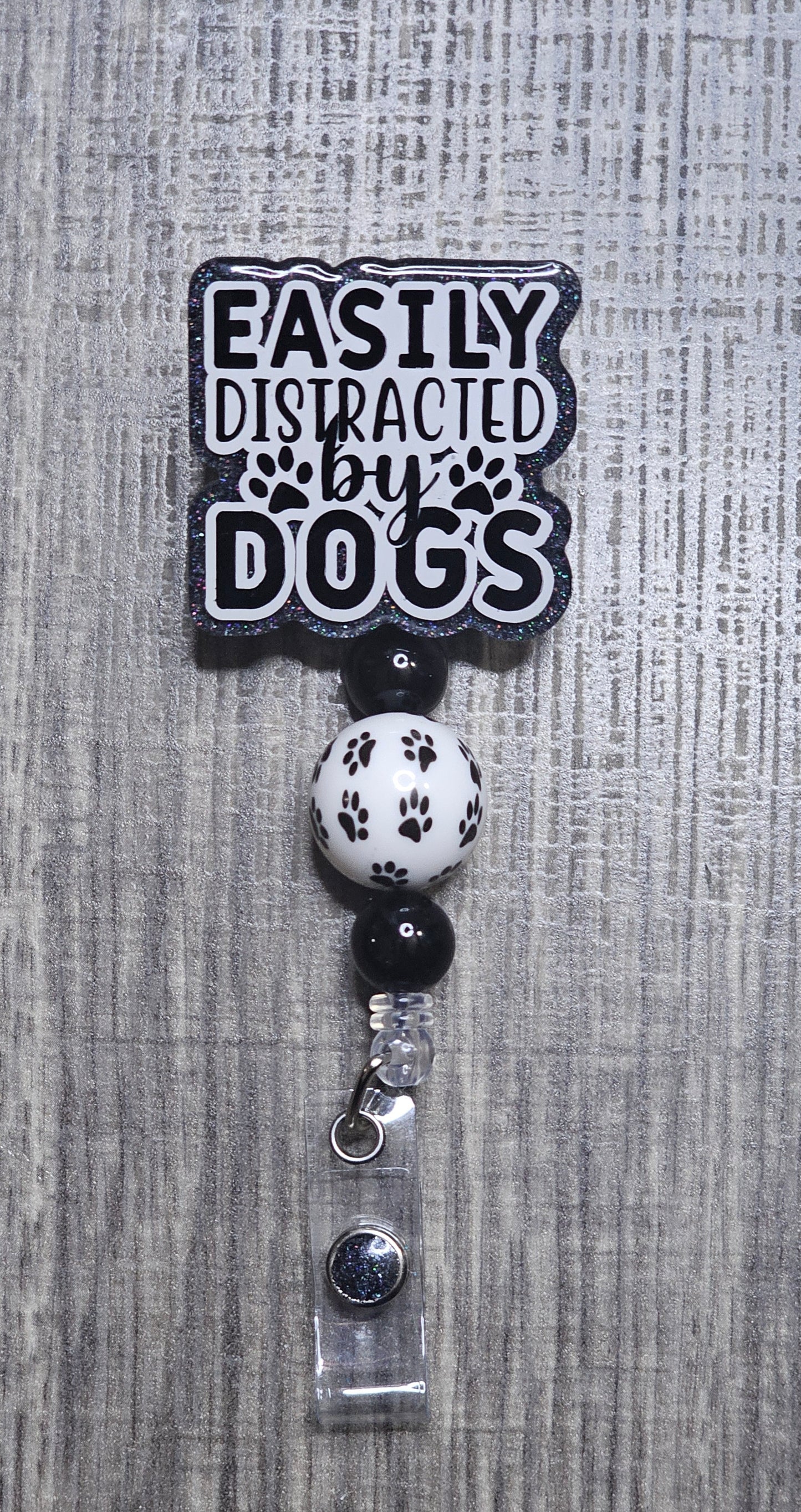 Badge holder with 'Easily Distracted by Dogs' text on a gray textured background