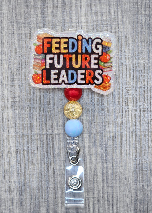 Badge reel with the words "Feeding Future Leaders" in a creative, colorful manner, surrounded by books and apples, with creatively matching decorative beads.