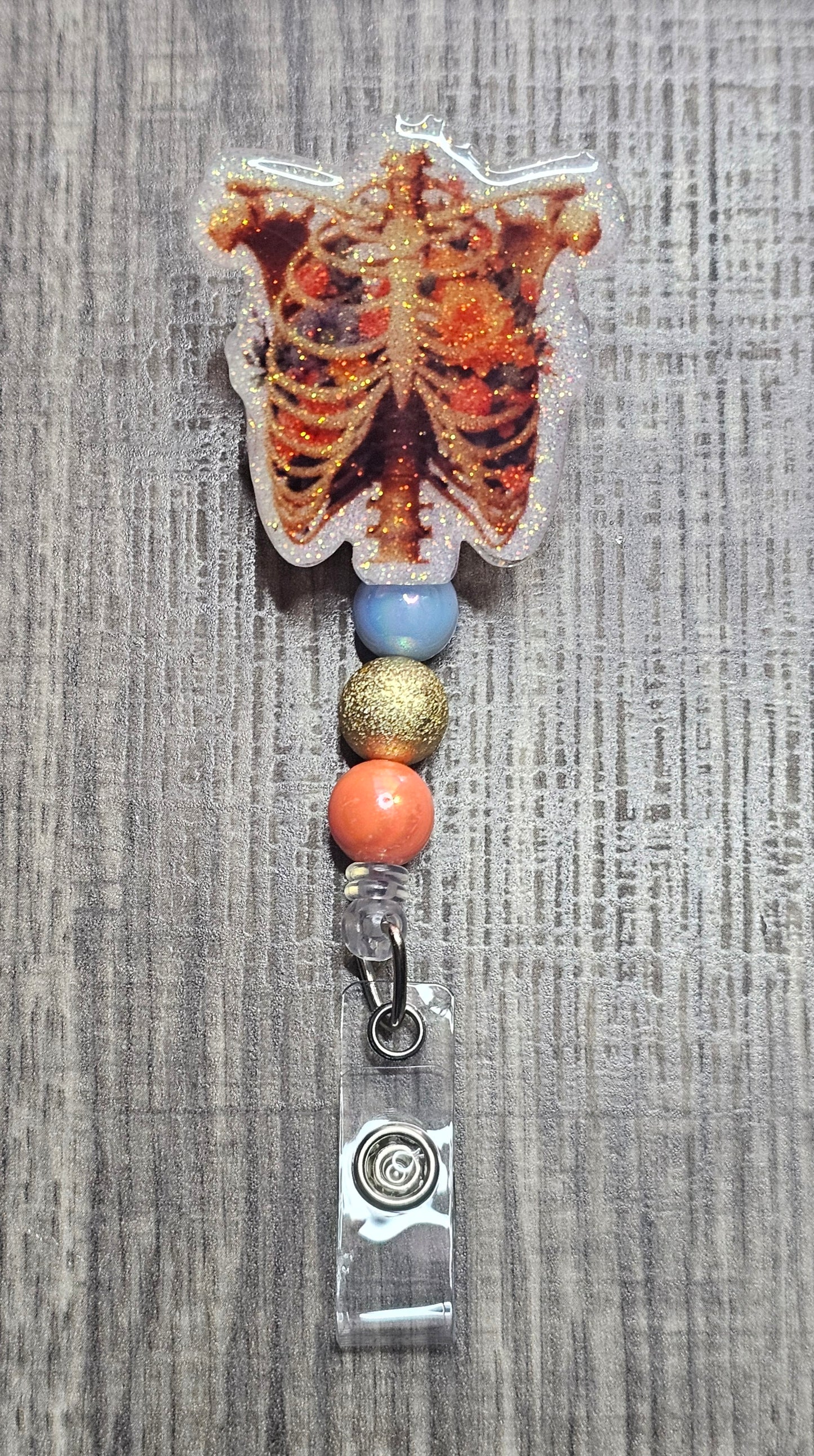 Anatomical ribcage badge reel with colorful flowers growing inside the bone structure, featuring pink and white beads.