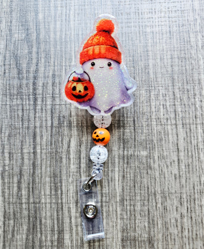 Cute ghost with an orange fall hat and a jack-o'-lantern trick-or-treat bucket on a Halloween-themed badge reel.