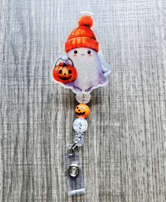 Cute ghost with an orange fall hat and a jack-o'-lantern trick-or-treat bucket on a Halloween-themed badge reel.